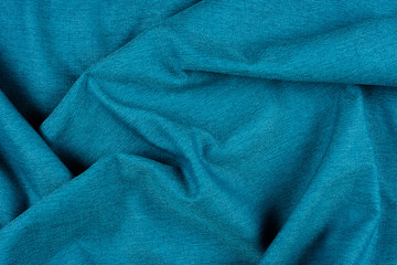 Bright blue fabric texture with folds. 