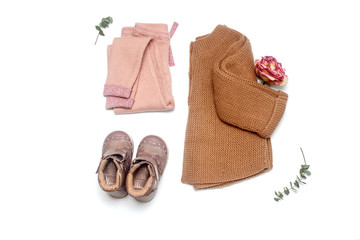 Little lady trendy fashion clothes set on white background top view. Leggings, boots and jacket. Fashionable pastel muted shades. Modern and casual outfit. Shopping. Flat lay.