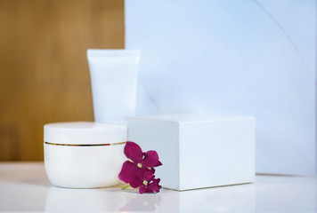 White cosmetic containers on white stand on a table