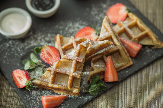 Homemade square Belgian waffles with ricotta cheese, chocolate, strawberries and cherries for breakfast. Selective focus. View from above