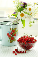 A bouquet of wildflowers and a glass bowl of red currant