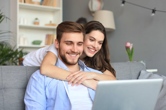 Young Couple Doing Some Online Shopping At Home, Using A Laptop On The Sofa.