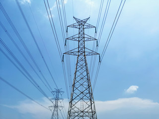 Low Angle View of High Voltage Tower and Power Lines Against Blue Cloudy Sky