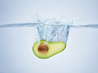 avocado drops in the water scattering a lot of sprays and drops