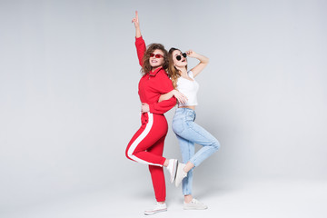 Two sporty woman at casual sportive style posing on gray background!