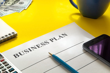 Strategy business plan with pen, coffee and money on yellow table.