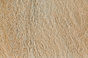 Ripples on the water on the sandy shore.