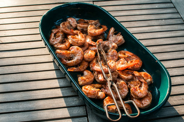 Ceramic dish with spicy grilled shrimps closeup on wooden rustic table background