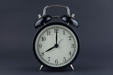 Black alarm clock on black background and seeting time at 8 o'clock.