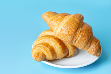 Croissant in a white plate on color background