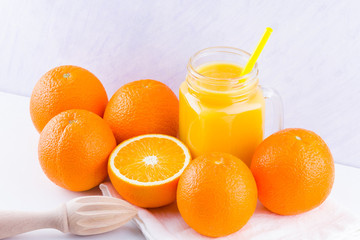 Orange fruits and juice on white background. Citrus fruit for making juice with manual juicer. Oranges on white napkin. Mason jar with orange juice