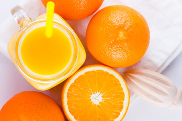 Orange fruits and juice on white background. Citrus fruit for making juice with manual juicer. Oranges on white napkin. Mason jar with orange juice