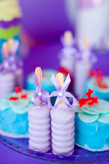 Birthday party concept. Table for kids with cupcakes with blue and red top and decored items in bright blue and purple colors. Summer season delicious on the party. Sea time theme on the candy bar