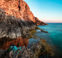 Golding light hitting the cliffs, contrasting with the blue sea and rope