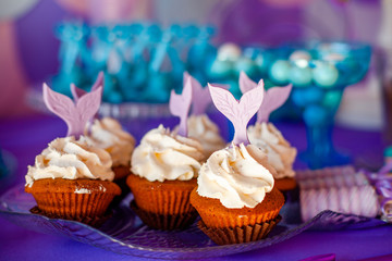 Birthday party concept for girl. Table for kids with cupcakes with withe topind decored purple...