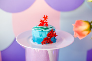 Birthday party concept. Table for kids with cupcakes with blue and red top and decored items in bright blue and purple colors. Summer season delicious on the party. Sea time theme on the candy bar