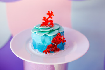 Birthday party concept. Table for kids with cupcakes with blue and red top and decored items in bright blue and purple colors. Summer season delicious on the party. Sea time theme on the candy bar