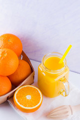 Fototapeta na wymiar Orange fruits and juice on white background. Citrus fruit for making juice with manual juicer. Oranges in wooden box on white napkin. Mason jar with orange juice