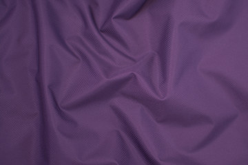 Silk crumpled fabric purple. View from above. Textile and texture concept - close up of crumpled silk violet wavy fabric background