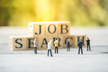 Miniature people, candidates and wooden word block "JOB SEARCH". Human resource concept, recruiting, hiring process.