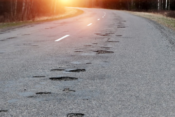 The road in disrepair with a lot of potholes. Cars go with the risk of breakdowns.