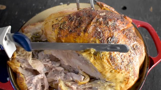 carving baked whole turkey with herbs with electric knife