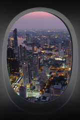 Fototapeta na wymiar sunset cityscape of Bangkok through window of aircraft