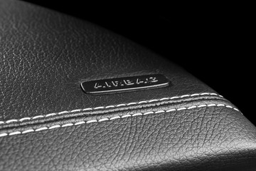 Modern sport car leather interior. Part of leather car cockpit details with stitching. Car detailing. Perforated leather cockpit with airbag . Black and white