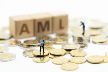 Money laundering concept. Miniature people, financial criminal on pile of coins and wooden word...