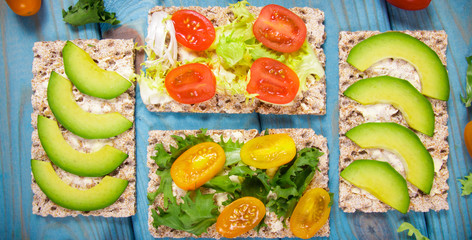 Healthy snack from wholegrain rye crispbread cracker with cherry tomatoes, avocado and salad....