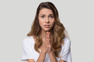 Young woman over grey background cupped hands in praying gesture