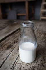 Miniature milk bottle with milk inside on a dark wood rustic table