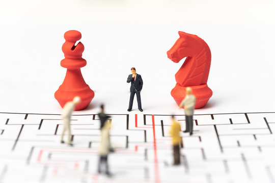 Miniature people, businessman and chess pieces in the labyrinth or maze figuring out the way out. Business concept, finding solution, strategic, and business opportunity.
