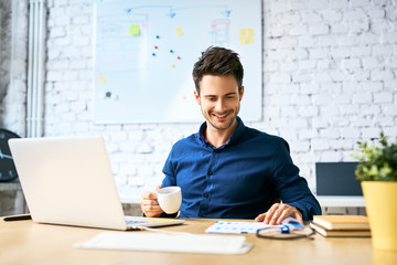 Young startup businessman drinking coffee and working using laptop and documents