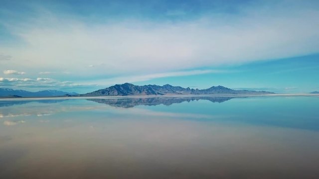 Bonneville Salt Flats located in Utah during Spring where a shallow layer or water creates a beautiful mirage of the sky and mountains in the background.