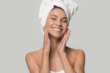 Smiling woman with towel on head touch clean healthy skin