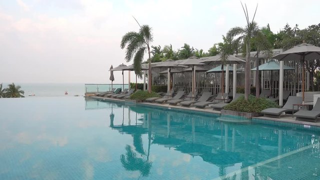 Sun loungers by a beautiful tropical infinity swimming pool