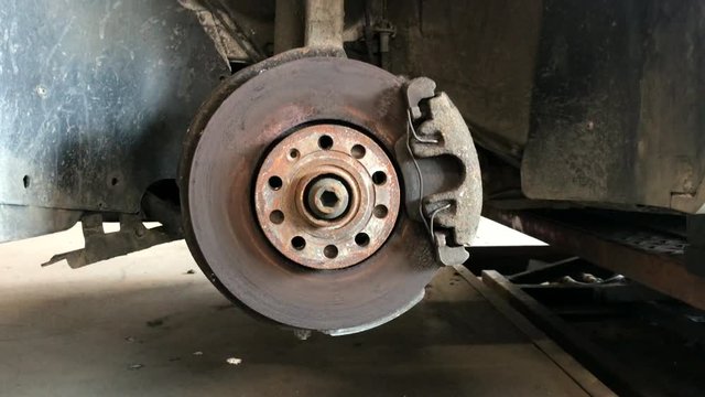 Rusty car brake disc with suspension components.