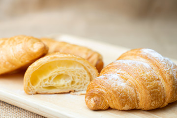 Croissant with icing on wooden plate