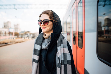 attractive young woman at the train station standing on the platform next to the train, girl waiting for the journey