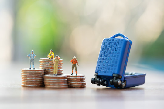 Travel and Saving Concept. Miniature people, travelers with backpack walking on coins stacks to miniature baggage.