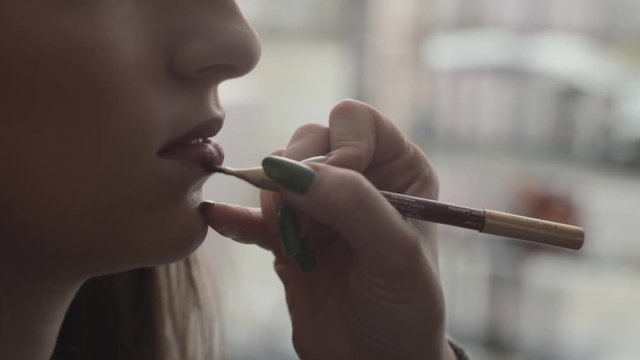 Close up of Hands applying makeup on lips with small brush, slow motion