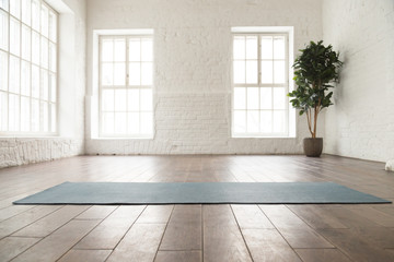 Unrolled yoga mat on wooden floor in yoga studio - obrazy, fototapety, plakaty