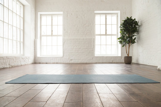 Unrolled yoga mat on wooden floor in yoga studio