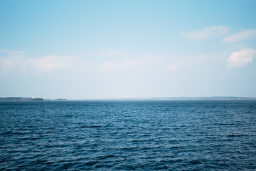 Obraz premium Beautiful deep blue sea, calm sea harmony of the water surface. Sunny sky and incredible lake. Live ocean with clouds on the horizon