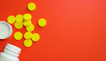 Yellow pills and white bottle with copy space on red background