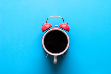 Morning coffee concept. Alarm clock and a cup of coffee all in one. Coffee on blue background.