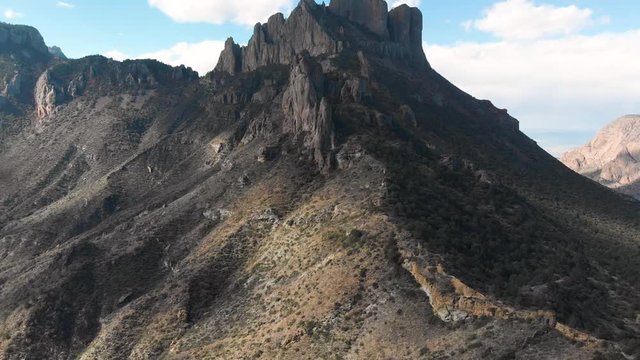 Push in aerial shot to moody high cliffs, rocky mountain top over the ridge
