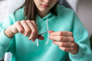 young girl cuts her nails with scissors close-up, macro
