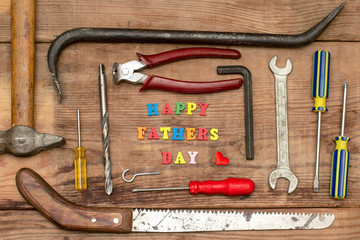 old tools on a wooden background and the text happy father's day colorful bright letters